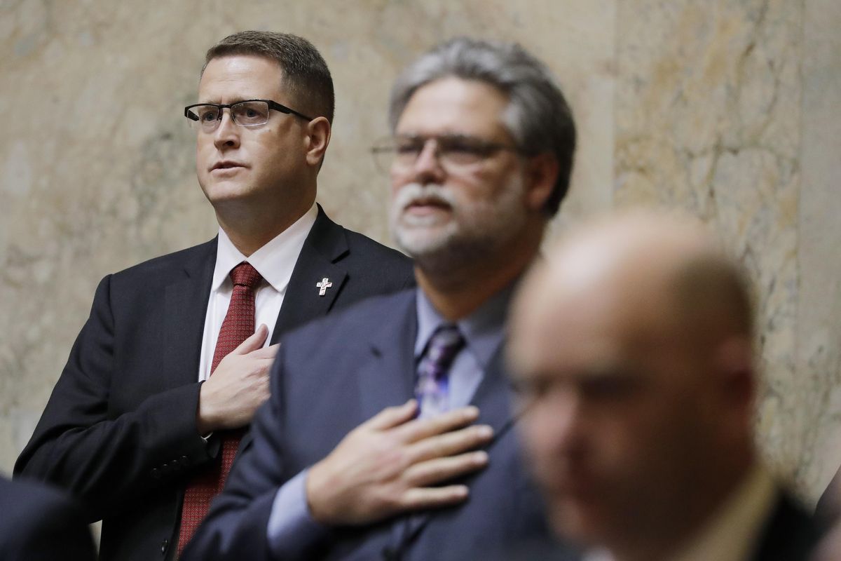 Rep. Matt Shea, R-Spokane Valley, left, stands at his desk on the House floor during the Pledge of Allegiance on Monday, Jan. 13, 2020, the first day of the 2020 session of the Washington Legislature in Olympia. Shea returned to the Capitol on Monday amid calls for his resignation in the wake of a December report detailing his involvement in anti-government activities. (Ted S. Warren / AP)