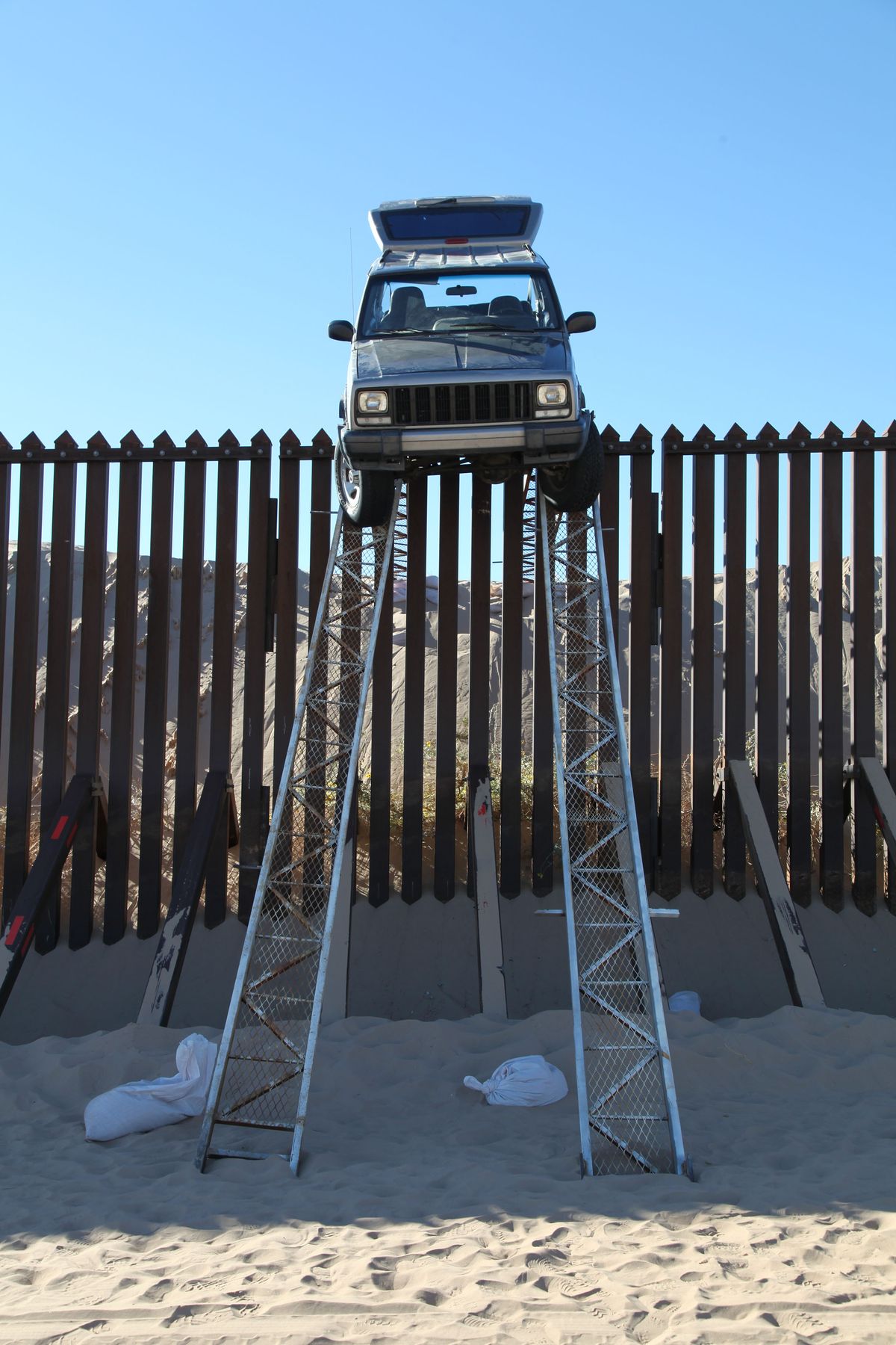 In this photo provided by the U.S. Customs and Border Protection, a silver Jeep Cherokee that suspected smugglers were attempting to drive over the U.S.-Mexico border fence is stuck at the top of a makeshift ramp early Wednesday, Oct. 31, 2012 near Yuma, Ariz. U.S. Border Patrol agents from the Yuma Station seized both the ramps and the vehicle, which stalled at the top of the ramp after it became high centered. The fence is approximately 14 feet high where the would-be smugglers attempted to illegally drive across the border. The two suspects fled into Mexico when the agents arrived at the scene. (U.s. Customs And Border Protection)