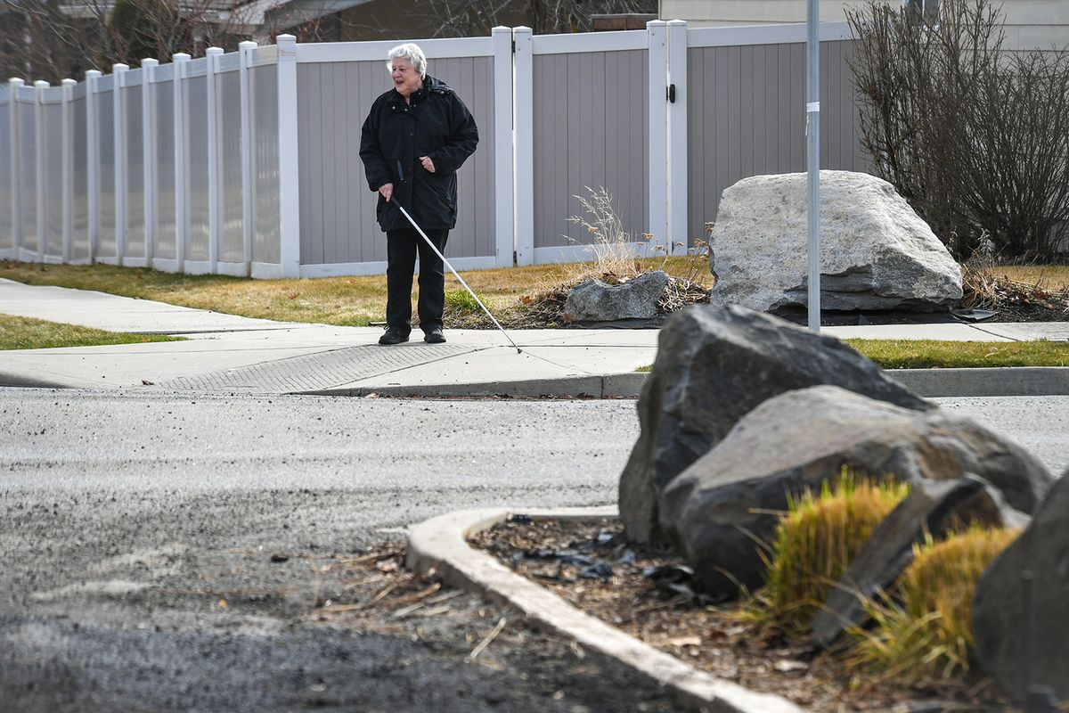 Alco Canfield, 73, who is blind, pauses her outing at the corner of 42nd Avenue and Cook Street where the sidewalk ends, Friday, March 26, 2021, in Spokane.  (Dan Pelle/THESPOKESMAN-REVIEW)