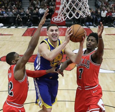 In this Jan. 17, 2018 file photo, Golden State Warriors’ Klay Thompson (11) shoots between Chicago Bulls’ Kris Dunn (32) and Justin Holiday, right, during the second half of an NBA basketball game. (Charles Rex Arbogast / Associated Press)
