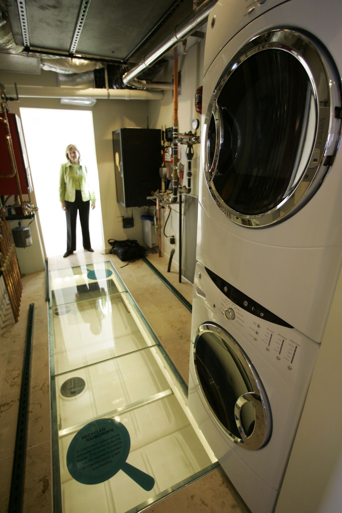 Anne Rashford, SmartHome exhibit project manager, looks in at the laundry room,  where a reservoir under the floor collects rainwater to use in the garden.  (Associated Press / The Spokesman-Review)