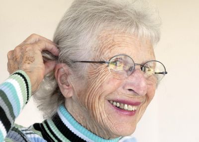 Melba Tschirley is hard of hearing and is delighted that the community center at Good Samaritan Village in Greenacres, where she lives, installed an induction looping system. Below, Tschirley shows her telecoil-equipped hearing aid. The hearing aid will beep to notify her when she is in range of an induction loop system and she can push the small button at the top to allow amplified and clarified sound to stream directly into her ears. (J. Bart Rayniak / The Spokesman-Review)