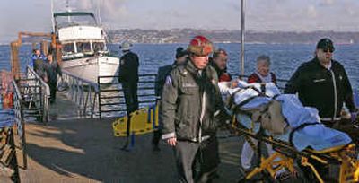 
A passenger from one of two small planes which collided near Tacoma on Tuesday is wheeled to an ambulance. In the background is the boat used to rescue two people from the water before one plane sank. Associated Press photos
 (Associated Press photo / The Spokesman-Review)