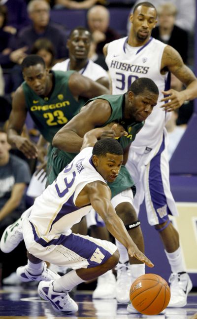 Huskies’ C.J. Wilcox dives for a loose ball as Oregon’s Olu Ashaolu defends. (Associated Press)