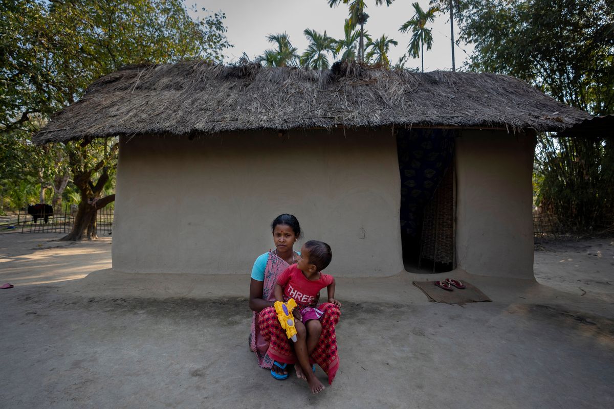 Champa Timungi, 25, sits outside her home in Mikir Bamuni village, Nagaon district, northeastern Assam state, India, Feb. 18, 2022. Timungi said she was beaten by the police despite being pregnant during a protest against the transfer of her family