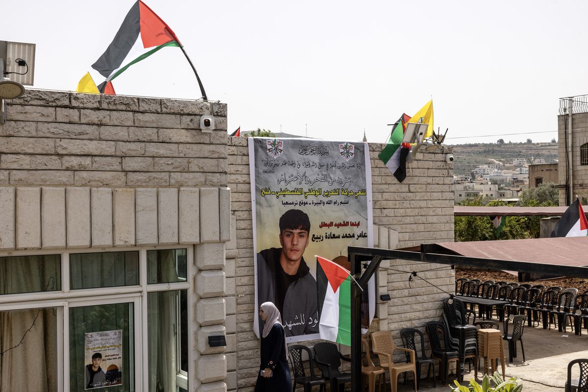 A woman walks past a giant poster showing Palestinian American Amer Rabee, 14, who was killed on Sunday. (Heidi Levine/For The Washington Post)