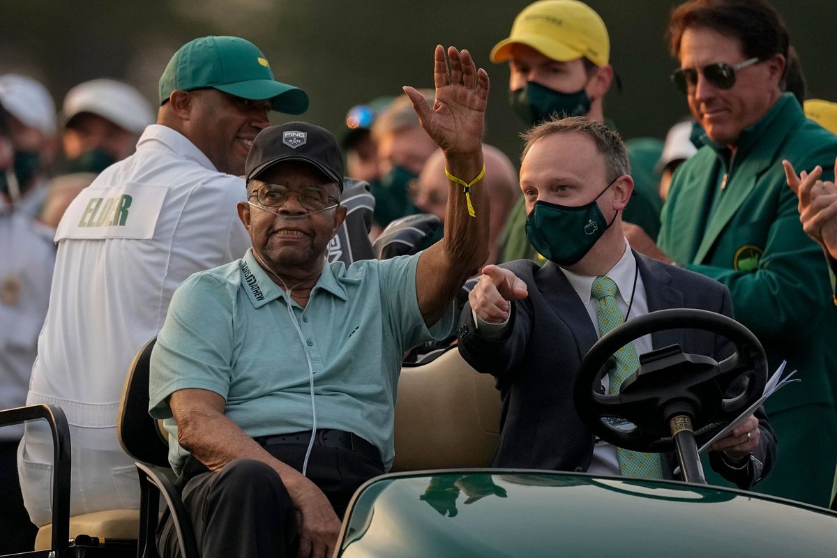 Lee Elder waves as he arrives for the ceremonial tee shots before the first round of the Masters golf tournament on Thursday, April 8, 2021, in Augusta, Ga. At far right is Phil Mickelson. Person at right in cart is unidentified. Elder broke down racial barriers as the first Black golfer to play in the Masters and paved the way for Tiger Woods and others to follow. The PGA Tour confirmed Elder’s death, which was first reported by Debert Cook of African American Golfers Digest. No cause or details were immediately available, but the tour said it spoke with Elder
