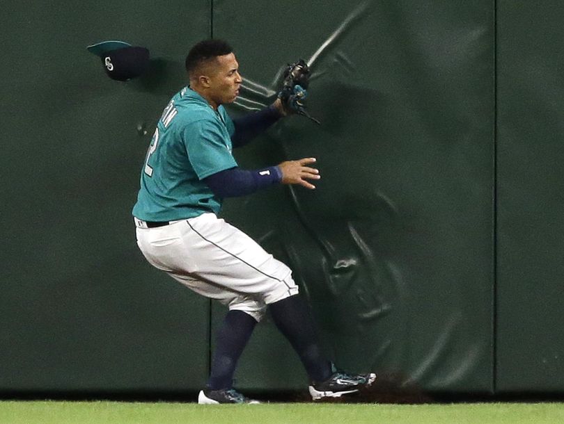 Mariners center fielder Leonys Martin loses his cap but holds on to the ball as he collides with the outfield wall after he caught a fly ball hit by Kansas City Royals’ Salvador Perez for the final out in Friday’s night’s game. The Mariners won 1-0. (Ted S. Warren / Associated Press)