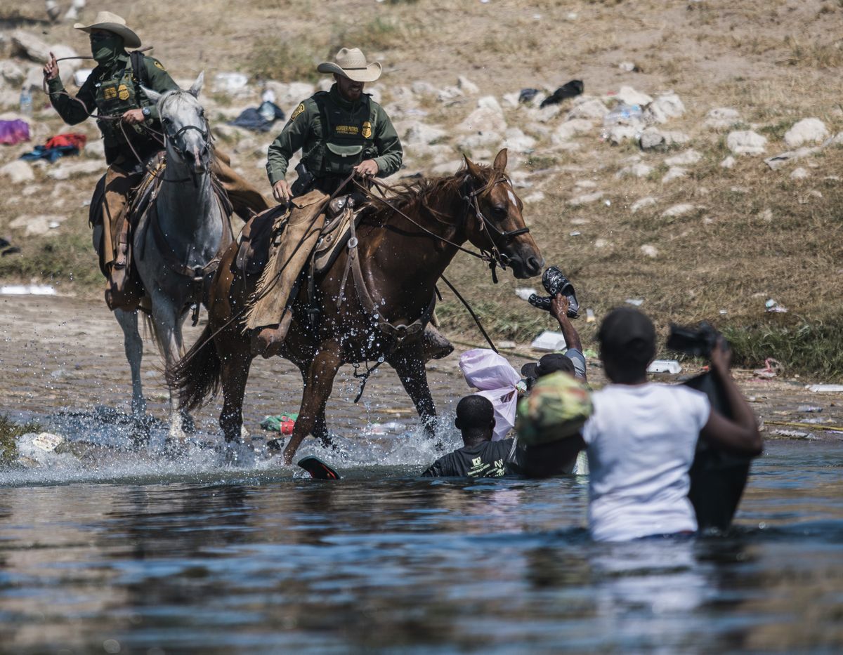 In this Sept. 19, 2021 photo, U.S. Customs and Border Protection mounted officers attempt to contain migrants as they cross the Rio Grande from Ciudad Acuña, Mexico, into Del Rio, Texas. The Border Patrol