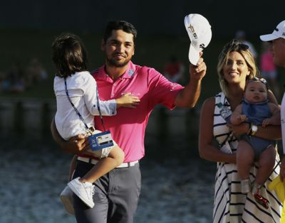 Jason Day of Australia, tips his hat as he walks off the 18th green with his family after winning The Players Championship golf tournament Sunday in Ponte Vedra Beach, Fla. Day is holding his son, Dash, as his wife, Ellie, holds Lucy. (Chris O'Meara / Associated Press)