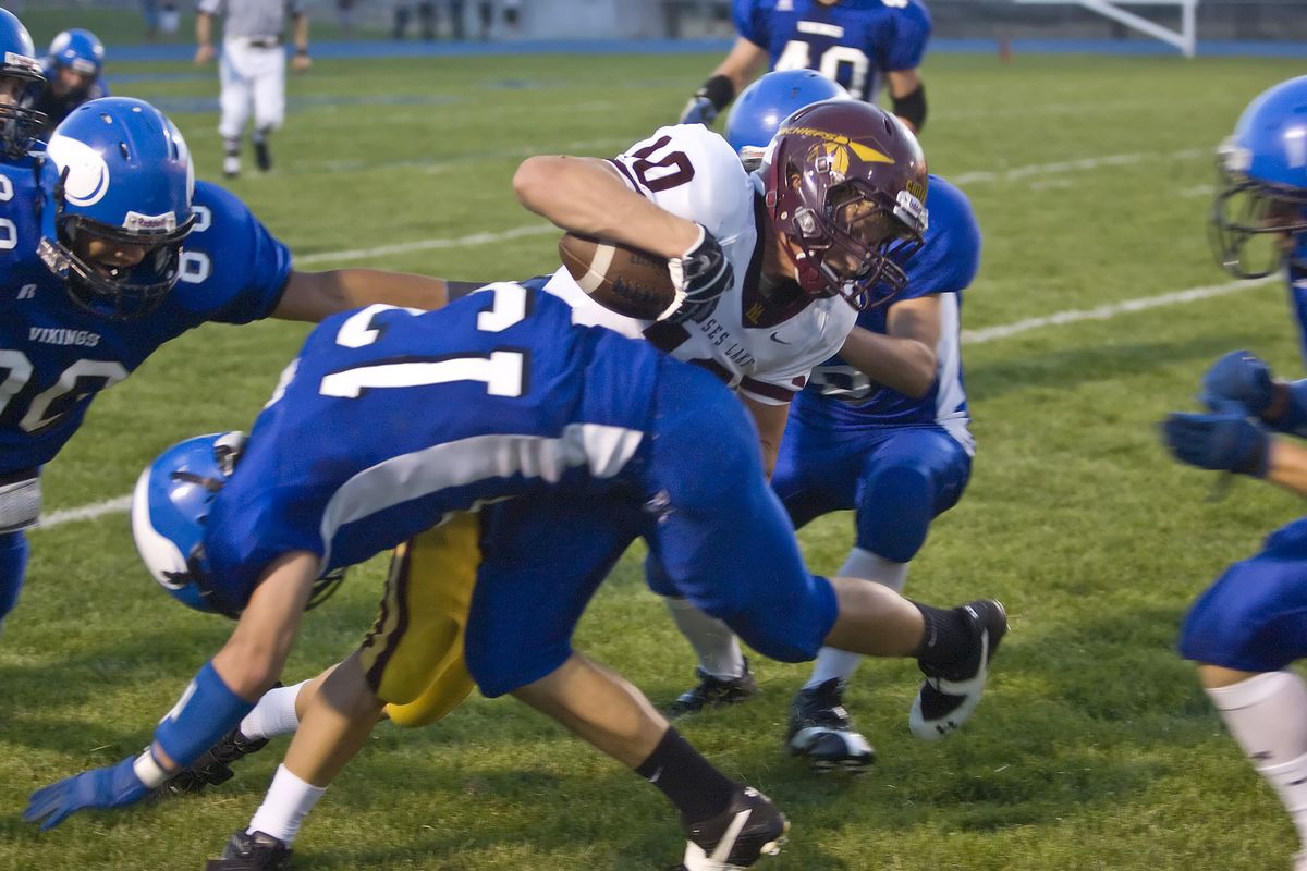 The Coeur d’Alene defense arrives en masse to bring down Cameron Law of Moses Lake. (BRUCE TWITCHELL)