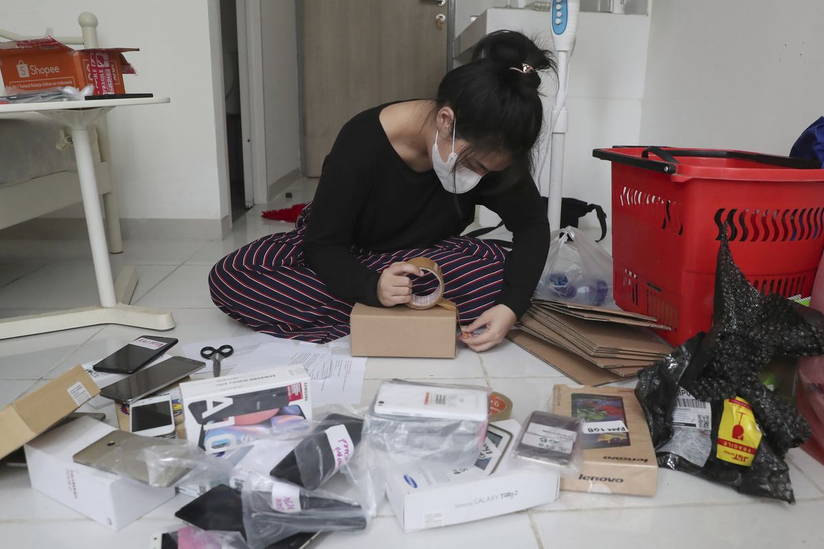 Indonesian journalist Ghina Ghaliya pack used mobile phones before shipping them to underprivileged children who lack internet access to study online, at her apartment in Tangerang, Indonesia, on Sept. 25, 2020. When a garbage collector came to Ghaliya