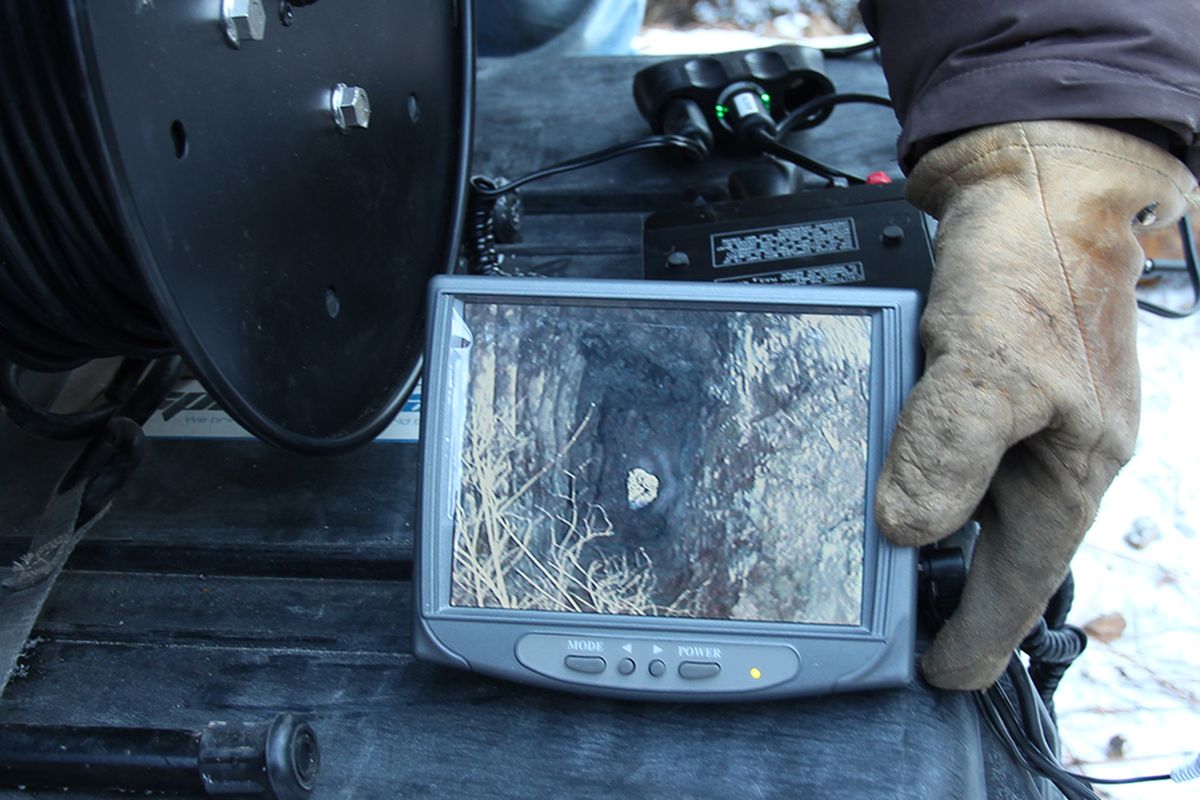 A BLM mine closure team leader from Salmon, Idaho, holds a monitor showing a live picture taken by a video camera that was lowered Saturday into the Evolution Mine in North Idaho. The shiny image on the monitor screen is believed to be ice at a point in the shaft where the camera’s descent was halted. (Bill Morlin)