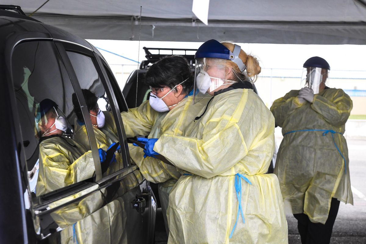 Medical workers attend to passengers in a vehicle entering the screening center Wednesday at the Spokane County Fair & Expo Center. (Dan Pelle / The Spokesman-Review)