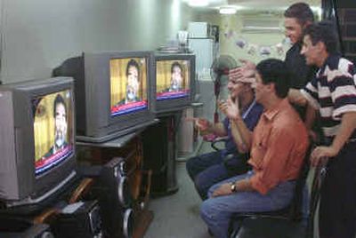 
Iraqis watch in an electonics store as former Iraqi President Saddam Hussein appears at a courtroom hearing on Thursday.
 (The Spokesman-Review)