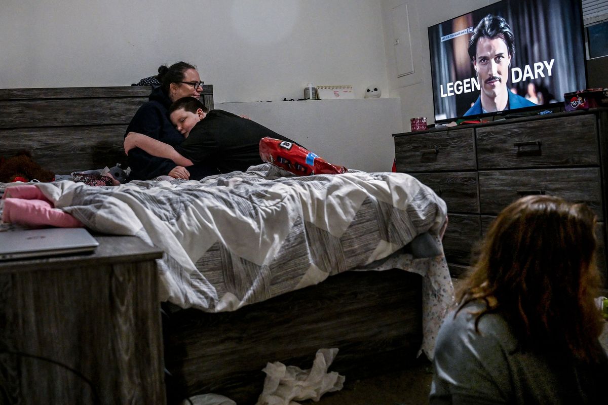 Kelley Kenplin holds her son Michael Osterhout, 9 as her daughter Ava Osterhout, 7 plays with toys before school at her home in Spokane on Thursday, December 4, 2025. The family moved into the home in August after being homeless in Spokane Valley. (Kathy Plonka/The Spokesman-Revie)