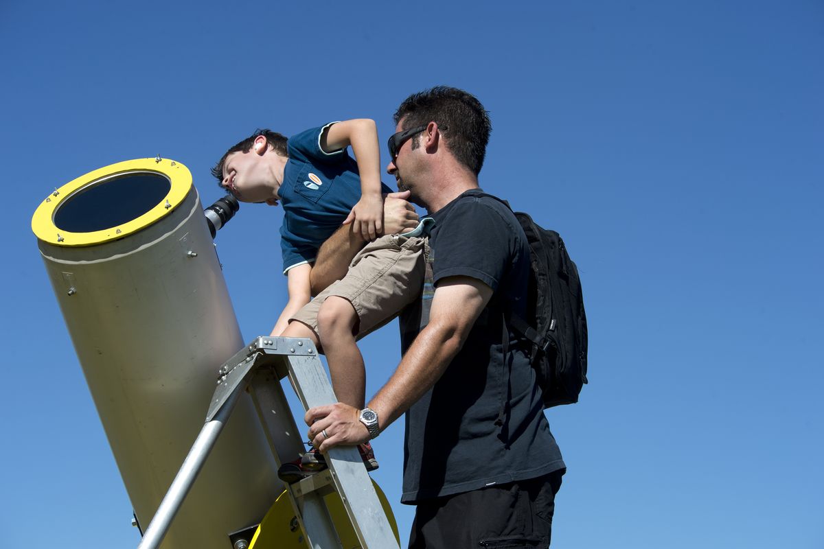 Steven Helnhofer helps his son Jack peek at sun spots through a telescope provided by Jim Picken and the Spokane Astronomical Society during Valleyfest at Mirabeau Park in 2014.  (Dan Pelle/The Spokesman-Review)