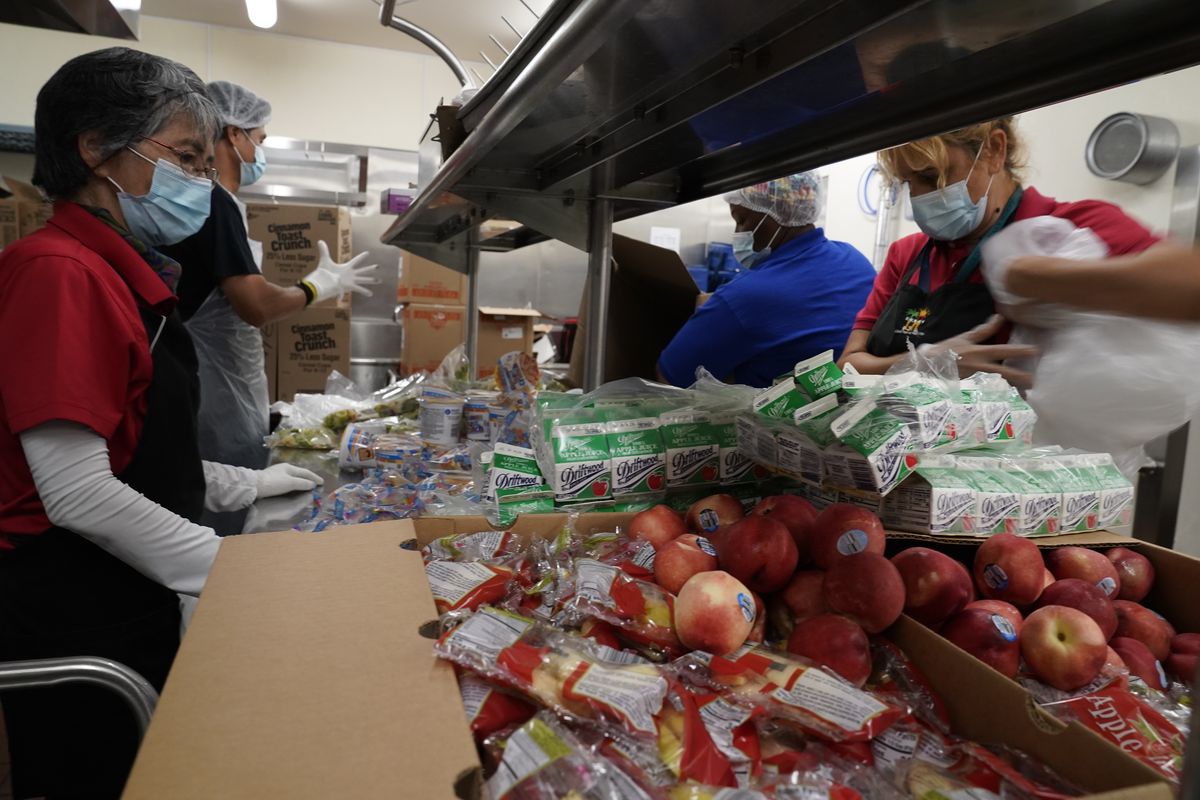 Los Angeles Unified School District food service workers from left, Tomoko Cho, Aldrin Agrabantes, April Thomas, and Marisel Dominguez, pre-package hundreds of free school lunches in plastic bags on Thursday, July 15, 2021, at the Liechty Middle School in Los Angeles. Flush with cash from an unexpected budget surplus, California is launching the nation