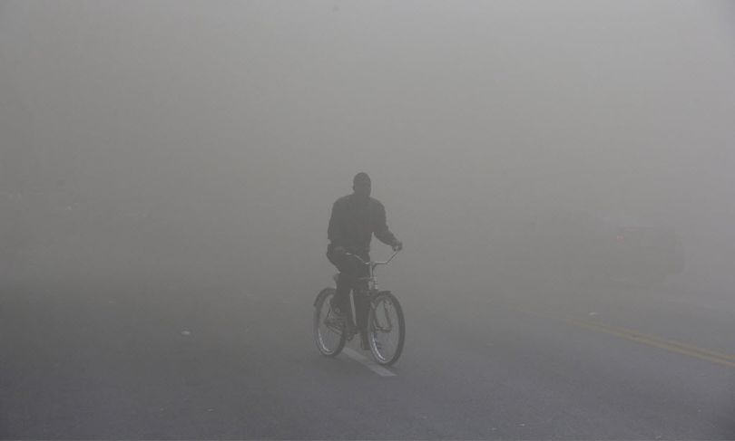 A man rides a bicycle through heavy smoke that is emitting from a nearby store on fire, Monday, April 27, 2015, during unrest following the funeral of Freddie Gray in Baltimore.  (AP Photo/Patrick Semansky)