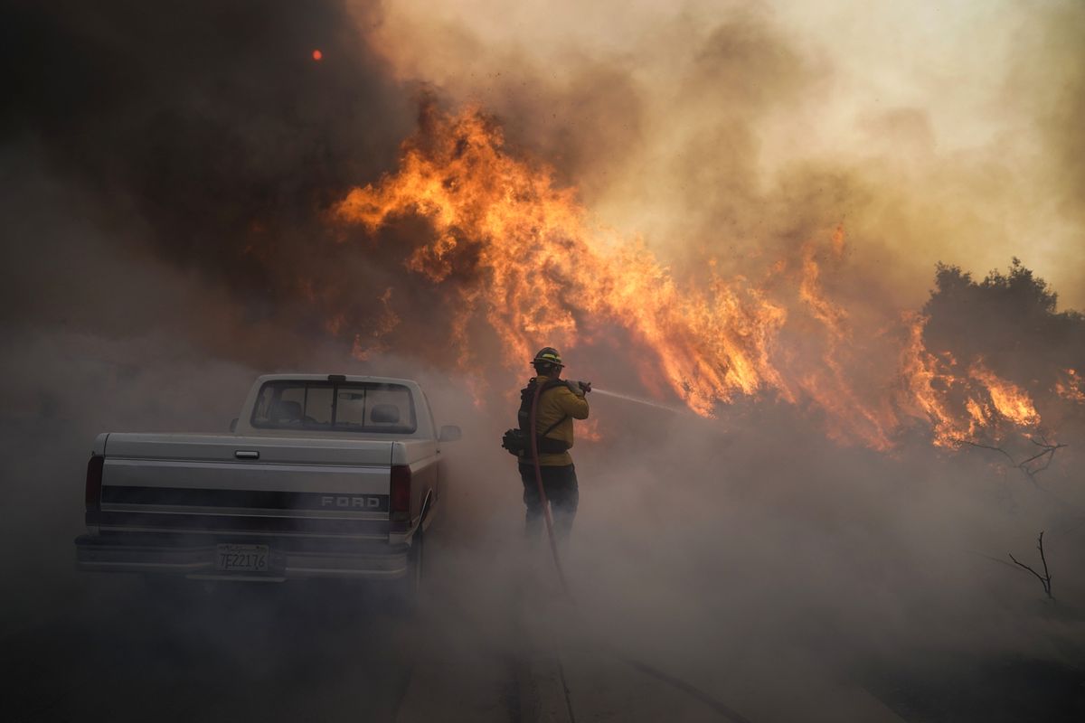 Firefighter Raymond Vasquez battles the Silverado Fire Monday, Oct. 26, 2020, in Irvine, Calif. A fast-moving wildfire forced evacuation orders for 60,000 people in Southern California on Monday as powerful winds across the state prompted power to be cut to hundreds of thousands to prevent utility equipment from sparking new blazes.  (Jae C. Hong)