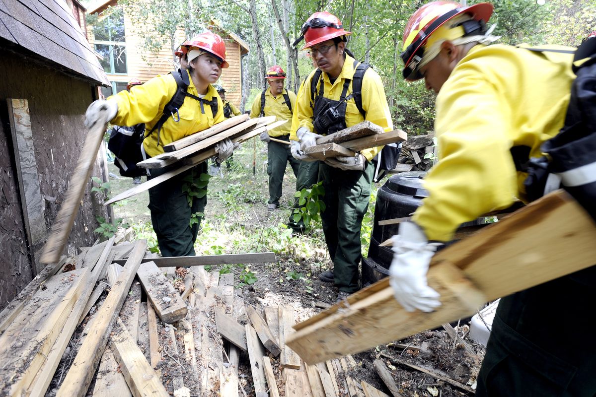 Firefighters from Rosewood, N.D., remove wood and debris from around a home near Boulder, Colo., on Thursday.  (Associated Press)