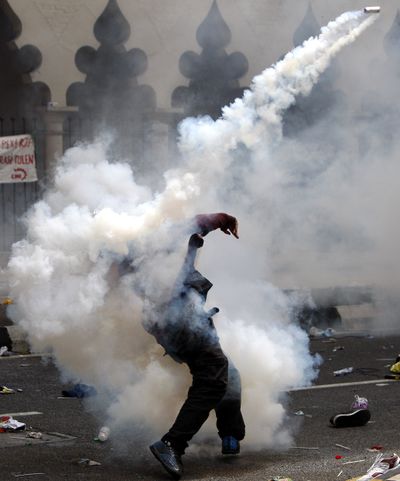 A protester throws back a tear gas canister fired by Malaysian police during a rally to demand electoral reforms in Kuala Lumpur, Malaysia, on Saturday. (Associated Press)