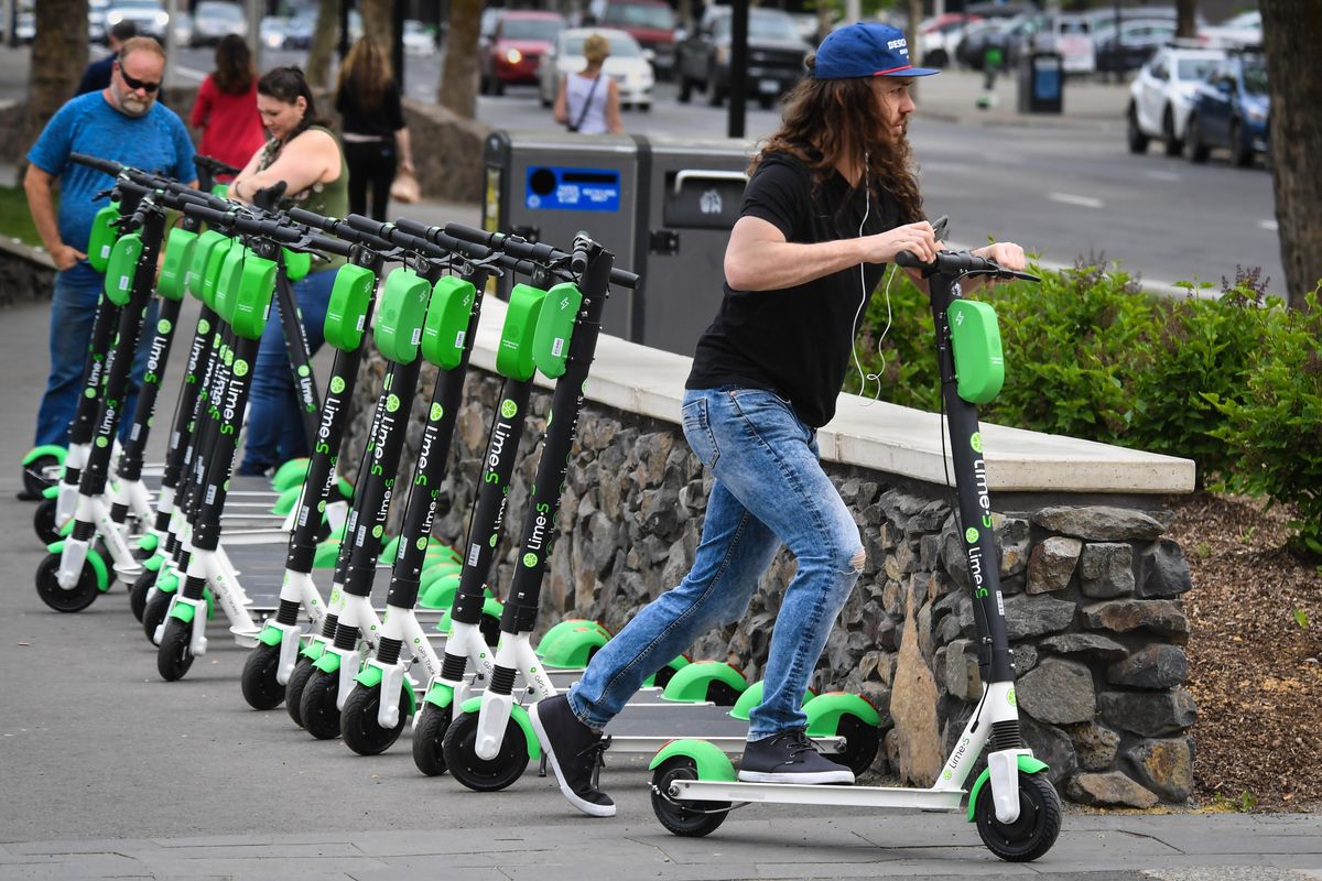 Jake Schreiber, of Spokane, checks out one of 35 Lime scooters available for use, Monday, May 13, 2019, in Riverfront Park. (Dan Pelle / The Spokesman-Review)