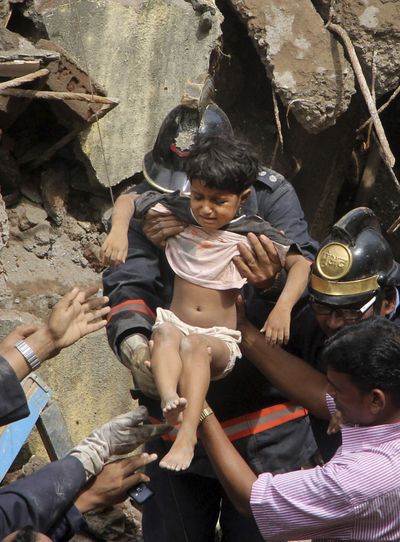 Workers rescue a girl from the debris of a collapsed building in Mumbai, India, Friday. The multistory apartment building fell in early Friday. (Associated Press)