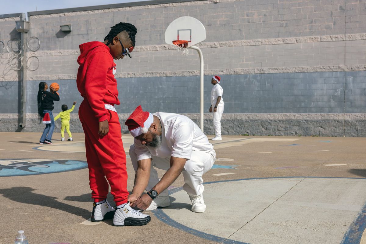 Kevin Porter ties the shoelaces of his son, Levi, during a Christmas with dads event at the Sanders Estes Unit prison in Venus, Texas, Dec. 19, 2025. (Dallas Morning News)