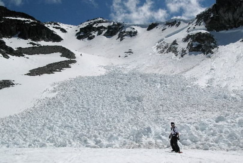 A snowboarder rides past debris from a large avalanche on Blackcomb mountain in Whistler, B.C. (Associated Press)