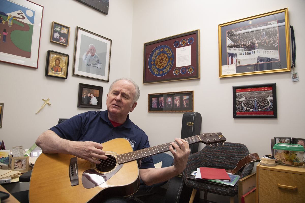 Rev. Patrick Conroy, S.J., plays guitar in his small office in Hemmingson Center at Gonzaga University Wednesday, Mar. 31, 2021 where he is assigned to campus ministry. Conroy said that he began playing guitar as a teen years ago, when “everybody wanted to be the fifth Beatle.” Long ago, he spent a year in Gonzaga law school decades ago before joining the Jesuits. Conroy recently spent 10 years as Chaplain of the U.S. House of Representatives.  (Jesse Tinsley/THE SPOKESMAN-REVI)