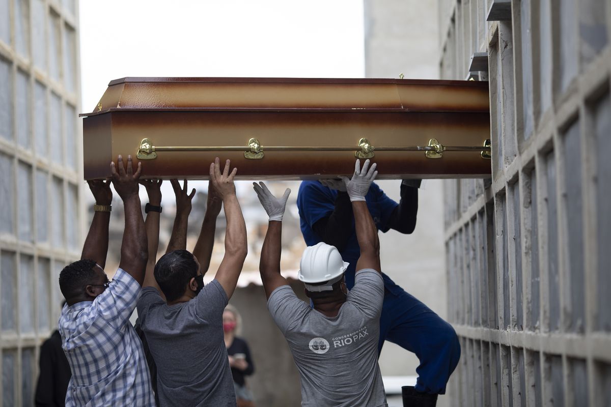 The remains of a woman who died from complications related to COVID-19 are placed into a niche by cemetery workers Tuesday at the Inahuma cemetery in Rio de Janeiro.  (Silvia Izquierdo)