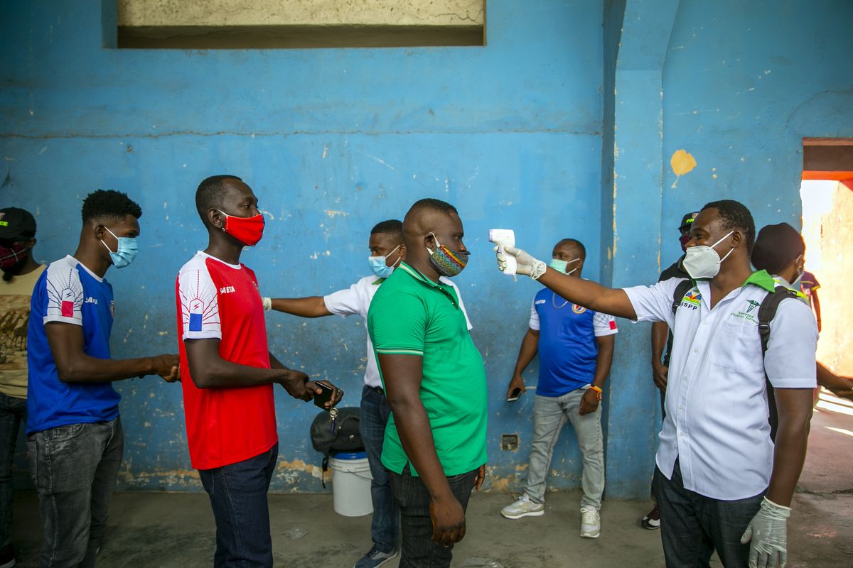 Health ministry workers check the temperature of mask-wearing fans as a precaution against the spread of the new coronavirus, before entering the stadium prior to the start of the CONCACAF World Cup qualifying soccer match between Haiti and Belize in Port-au-prince, Haiti, Thursday, March 25, 2021.  (Dieu Nalio Chery)