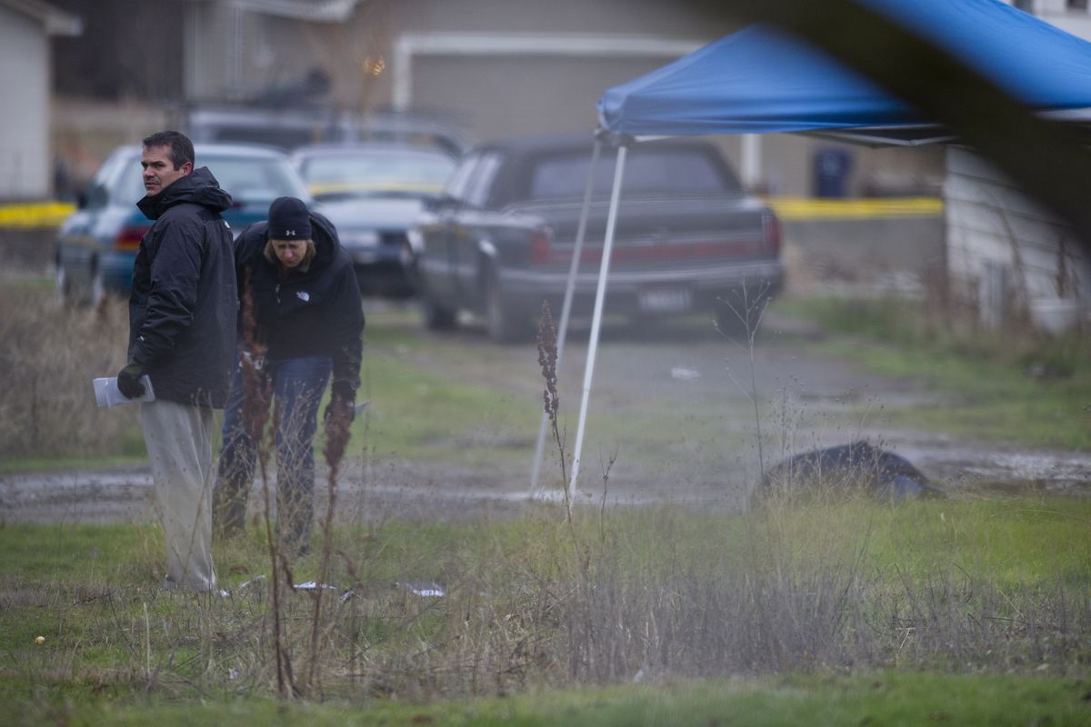 Crime scene investigators document the scene around where a body was found Friday morning in an alley near the intersection of West Bridge Avenue and North Cannon Street in Spokane. (Tyler Tjomsland)