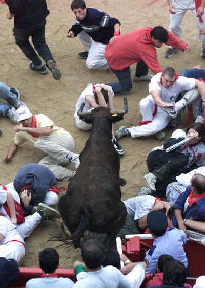 
People try to avoid a fighting bull as it enters Pamplona's bull ring after running through the streets of Pamplona, northern Spain, on Wednesday. 
 (Associated Press / The Spokesman-Review)