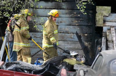 
Firefighters spray water on hot spots Tuesday after an early morning fire heavily damaged a detached garage in the 5200 block of East Fourth Avenue, destroying its contents.
 (Christopher Anderson / The Spokesman-Review)