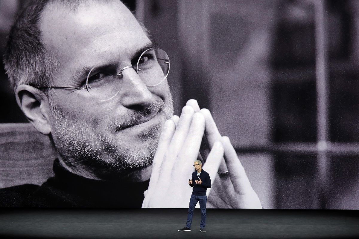 FILE - In this Sept. 12, 2017 file photo, with a photo of former Apple co-founder and CEO Steve Jobs projected in the background, Apple CEO Tim Cook kicks off the event for a new product announcement at the Steve Jobs Theater on the new Apple campus in Cupertino, Calif. Apple has become the worlds first company to be valued at $1 trillion, the financial fruit of tasteful technology that has redefined society since two mavericks named Steve started the company 42 years ago. (Marcio Jose Sanchez / Associated Press)