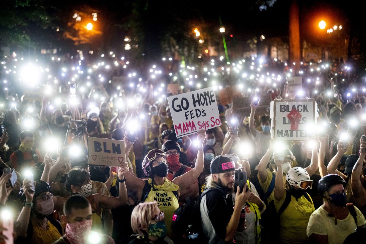 Hundreds of Black Lives Matter protesters hold their phones aloft on Monday, July 20, 2020, in Portland, Ore. Federal officers’ actions at protests in Oregon’s largest city, hailed by President Donald Trump but done without local consent, are raising the prospect of a constitutional crisis — one that could escalate as weeks of demonstrations find renewed focus in clashes with camouflaged, unidentified agents outside Portland’s U.S. courthouse.  (Noah Berger)