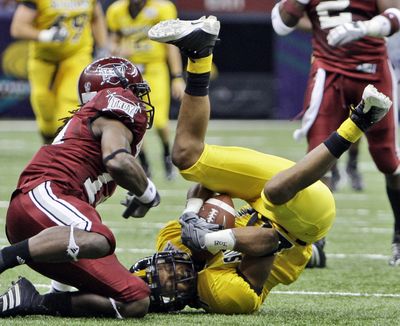 Southern Mississippi receiver William Spright is upended by Troy defender Jorrick Calvin.   (Associated Press / The Spokesman-Review)