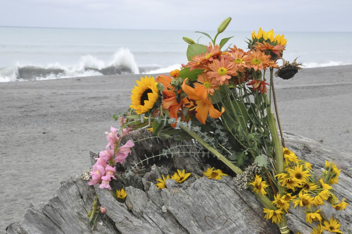 Flowers are rest on a large drift log yards from the breaking surf of the Big Lagoon beach near Trinidad, Calif. on Monday, Nov. 26, 2012. A family that tried to rescue their dog from powerful surf at the beach in Northern California were swept out to sea, leaving the parents dead and their 16-year-old son missing, authorities said. (Jose Quezada / The Times-standard)