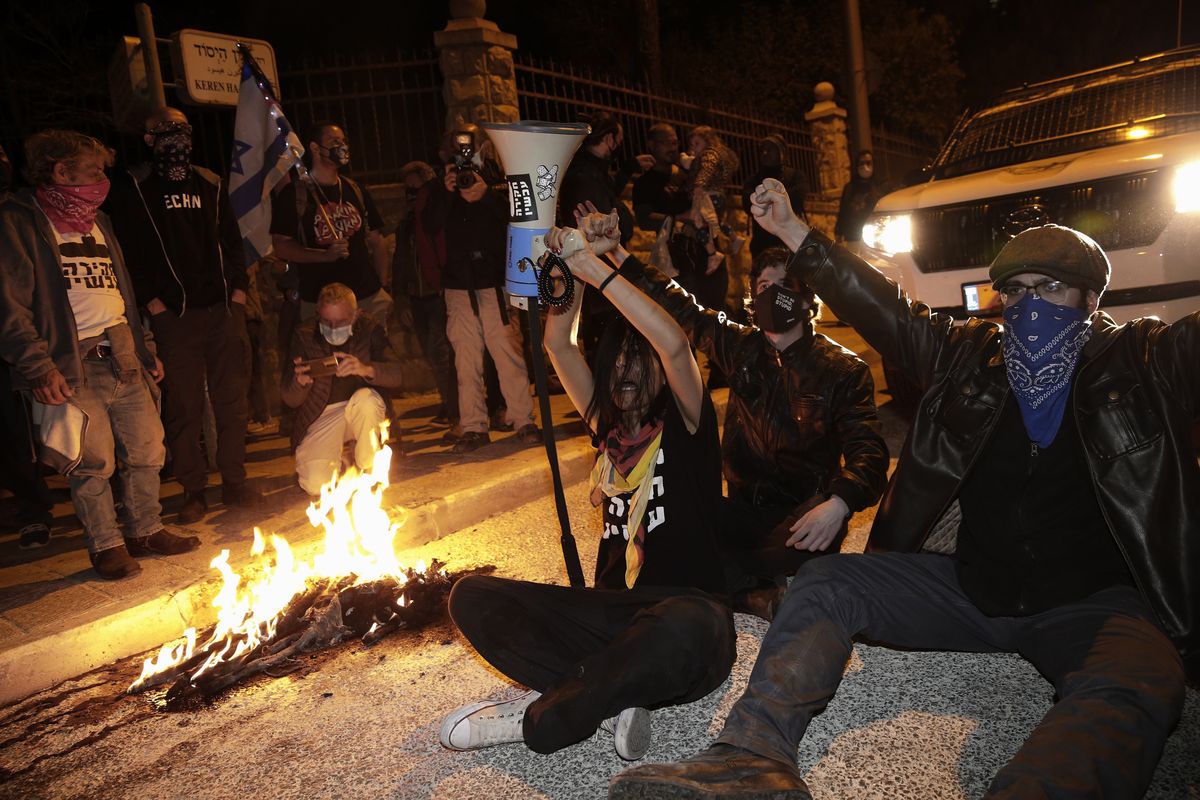 Israeli protesters chant slogans and block a road during a demonstration against Israeli Prime Minister Benjamin Netanyahu near his official residence in Jerusalem during the third nationwide coronavirus lockdown, Saturday, Jan. 2, 2021.  (Ariel Schalit)