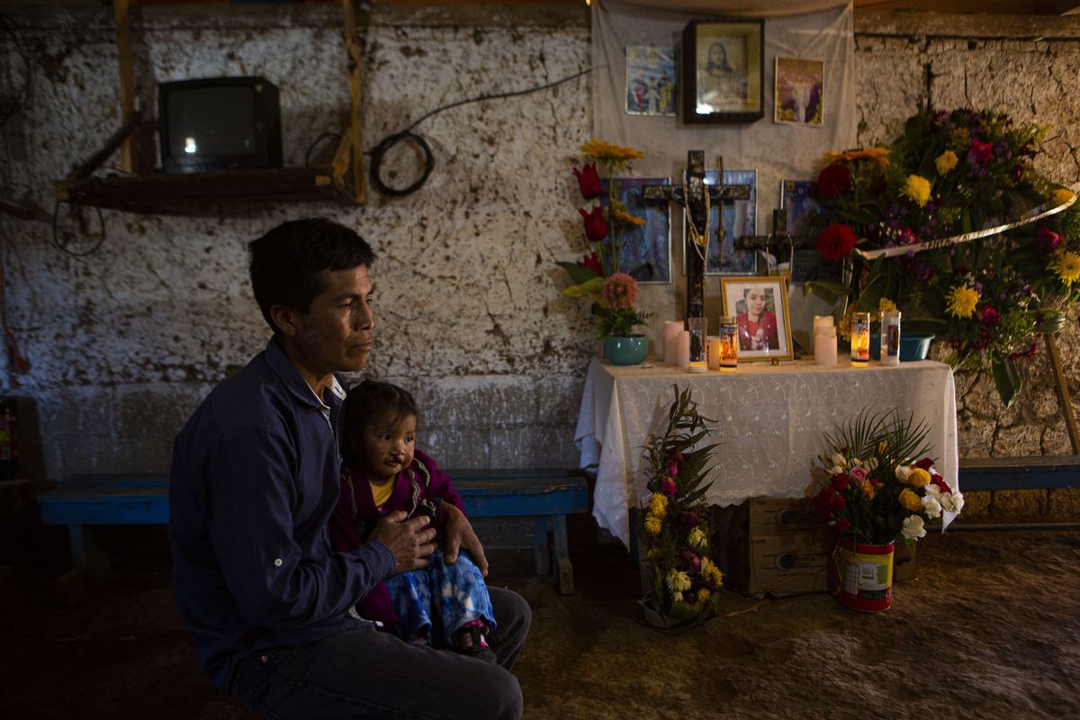 Ricardo Garcia and daughter Angela sit next to an altar adorned with photographs of his older daughter Santa Garcia, in his home in Comitancillo, Guatemala, Wednesday, Jan. 27, 2021. He believes his daughter Santa is one of the charred corpses found in a northern Mexico border state on Saturday. The country