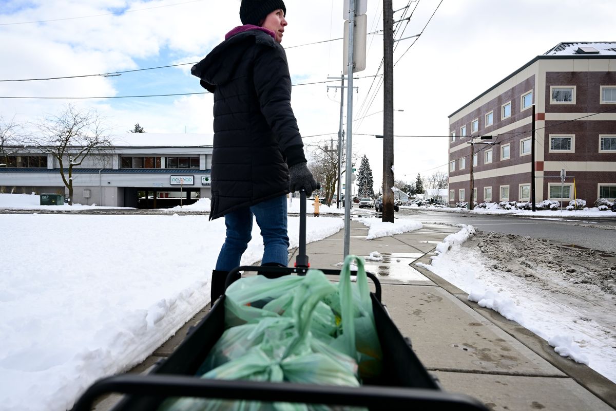 Shannon Lehman rolls food she received during a Second Harvest mobile distribution event toward her home in a wagon on Tuesday at Lidgerwood Elementary in Spokane.  (Tyler Tjomsland/The Spokesman-Review)