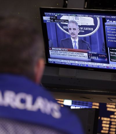 A specialist watches news Tuesday of the lawsuit against Standard & Poor’s Ratings Services, shown on a TV on the floor of the New York Stock Exchange. (Associated Press)
