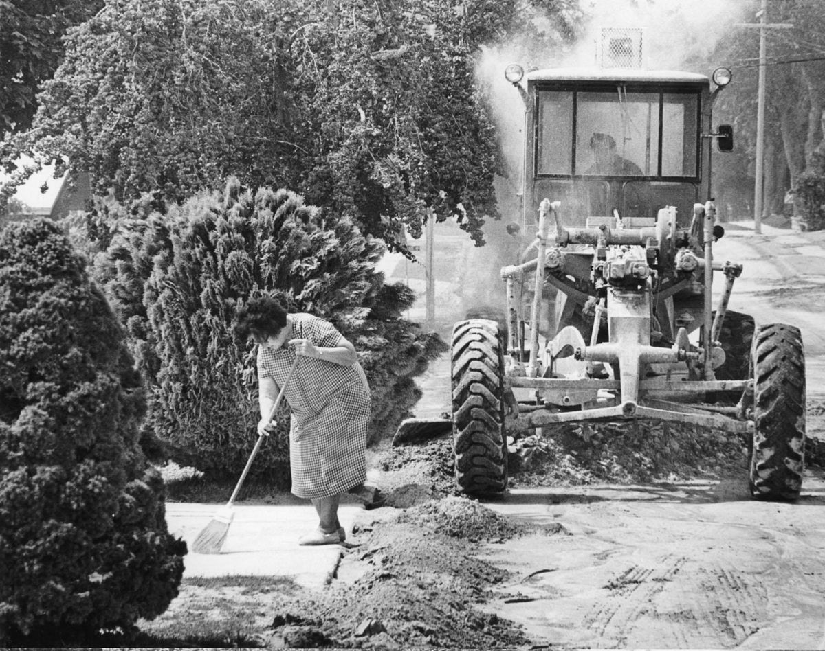 Amelia Kramer of Ritzville, Wash., works to get the ash off her sidewalk as a city employee uses a larger piece of equipment to get the street cleaned. Ritzville was the hardest hit town in Eastern Washington, receiving several inches of the ash. This photo was taken several days after the eruption of Mount St. Helens on May 18, 1980. The volcanic ash  helped create the rich soil that allows Washington farmers to grow over 300 different crops. (The Spokesman-Review archive)