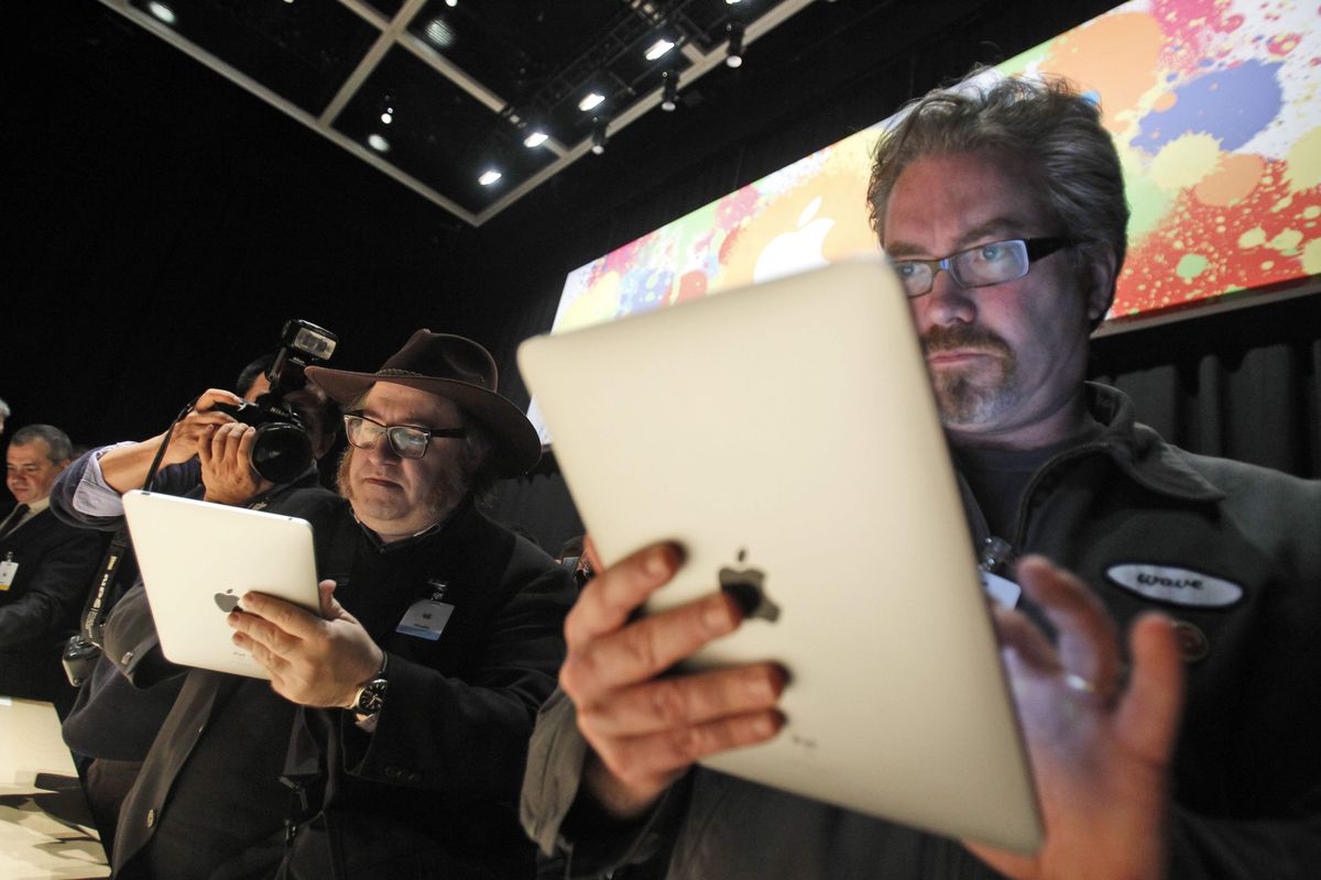 The Apple iPad is examined after its unveiling at the Moscone Center in San Francisco. (Associated Press)