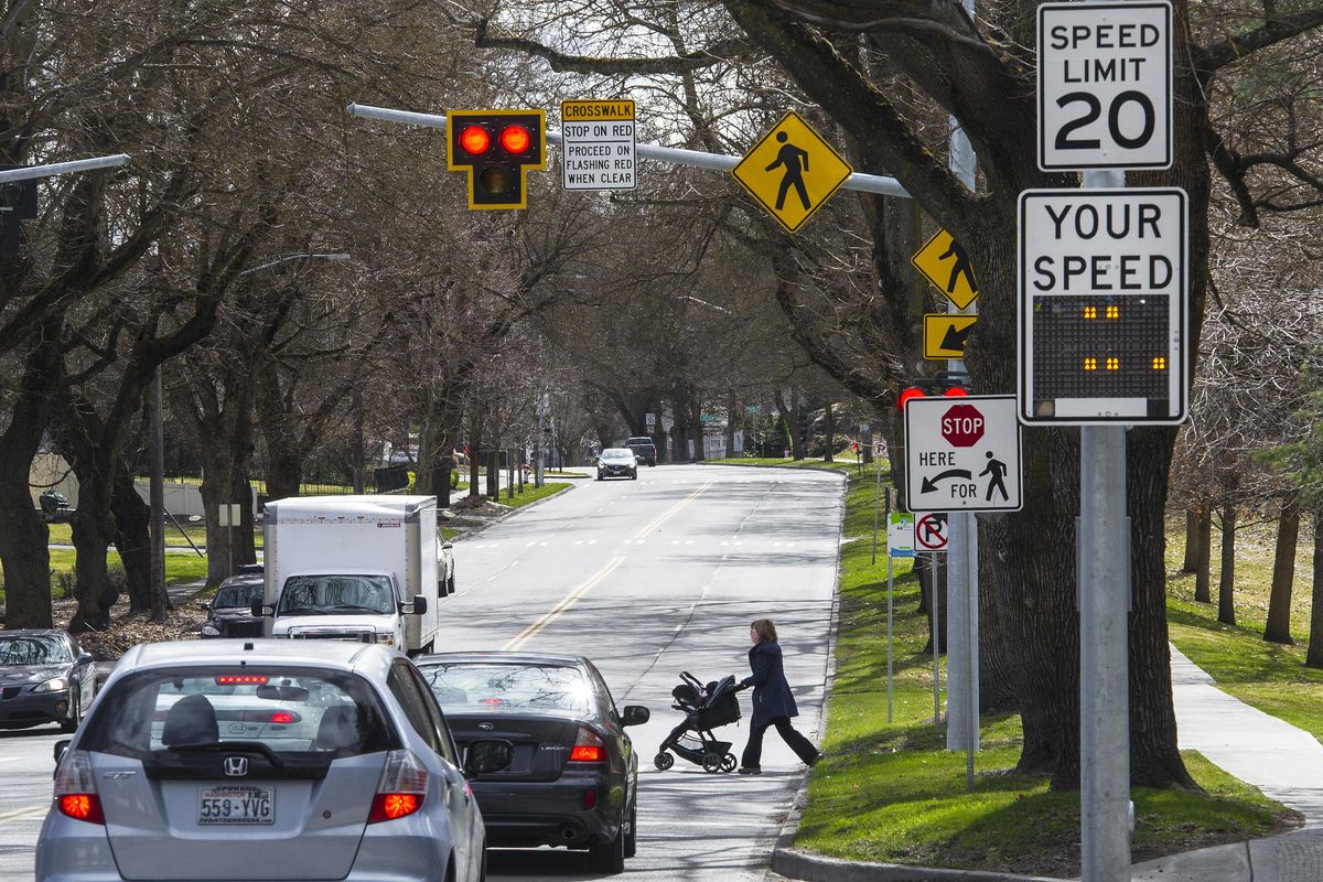 A pedestrian crosses Grand Boulevard at 18th Avenue, Wednesday, March 28, 2018. Some neighborhood representatives are suggesting the city consider a plan to lower speed limits to 20 mph around all city parks. (Colin Mulvany / The Spokesman-Review)