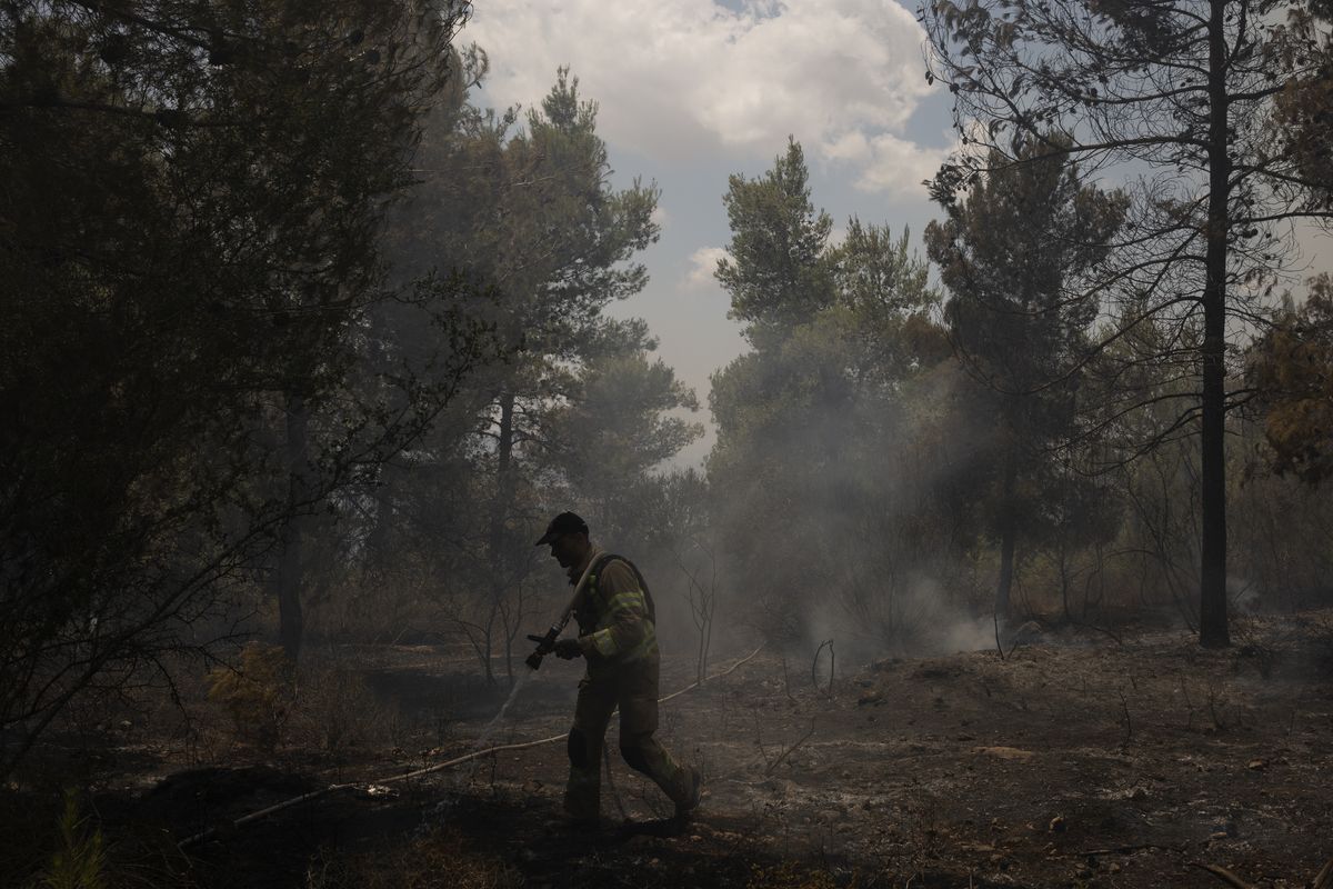 An Israeli firefighter works to extinguish a fire, on the second day of wildfires near Jerusalem, Monday, Aug. 16, 2021. Israel Fire and Rescue service said in a statement on Monday, that 45 firefighting teams accompanied by eight planes were working to contain five fires in the forested hills west of the city.  (Maya Alleruzzo)