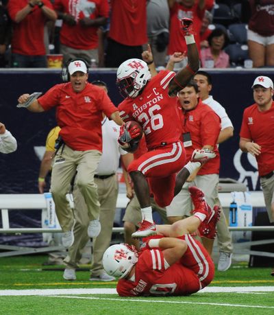 Houston cornerback Brandon Wilson (26) leaps over teammate Zach Vaughan (90) as he returns a missed field goal for a touchdown against Oklahoma in the second half of Houston’s 33-23 victory Saturday. (George Bridges / Associated Press)