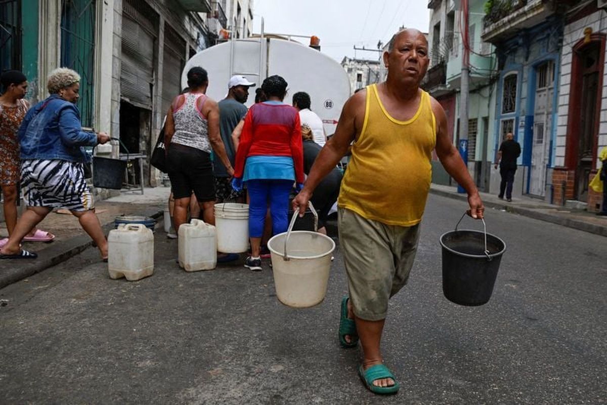 A man carries two buckets of water as severe fuel shortages have disrupted water pumping and distribution, in Havana, Cuba March 19, 2026.   (Norlys Perez/Reuters)